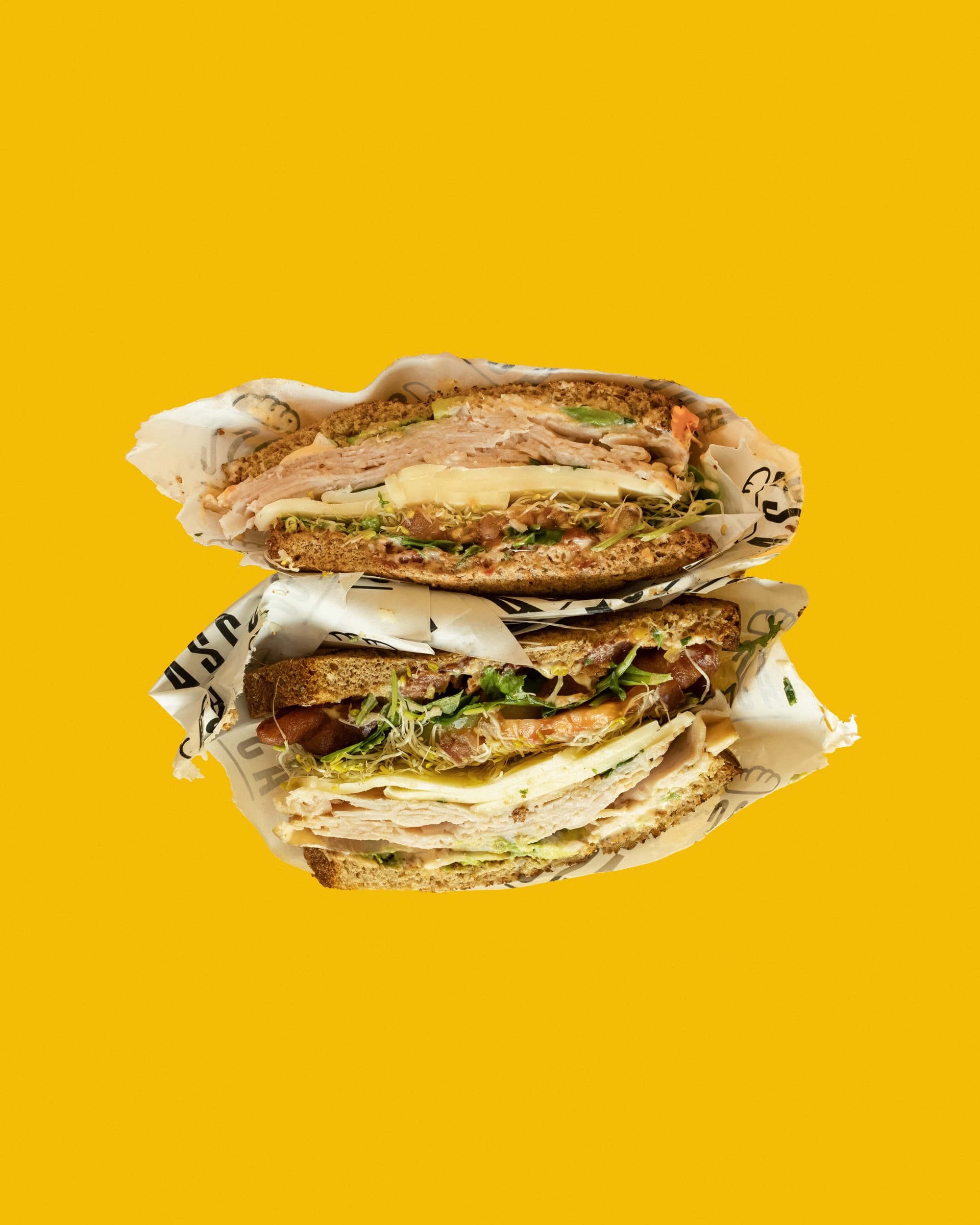 Two sandwich halves stacked on a vibrant yellow background