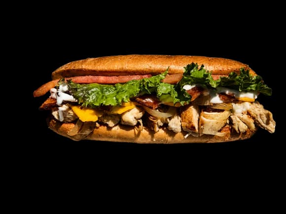 Grilled chicken ranch sandwich with bacon, cheese, tomatoes, and grilled onions